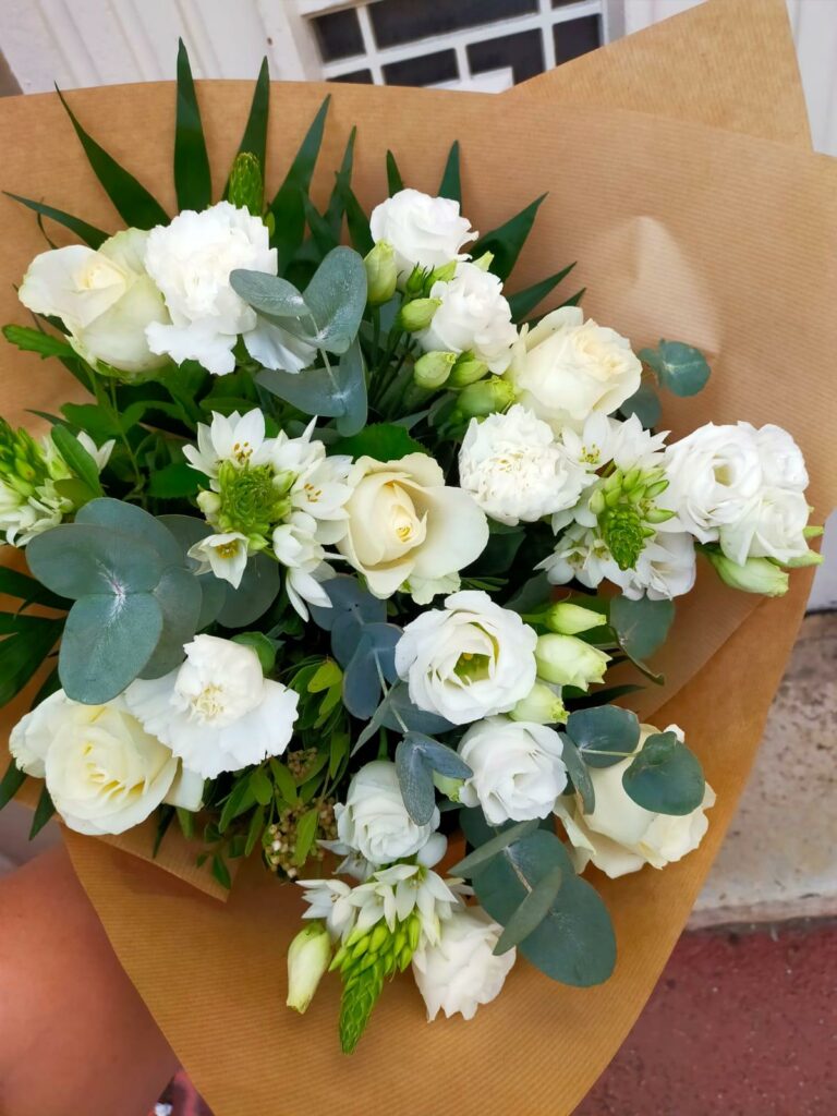 bouquet blanc il y a des lisianthus, des roses et de l’eucalyptus