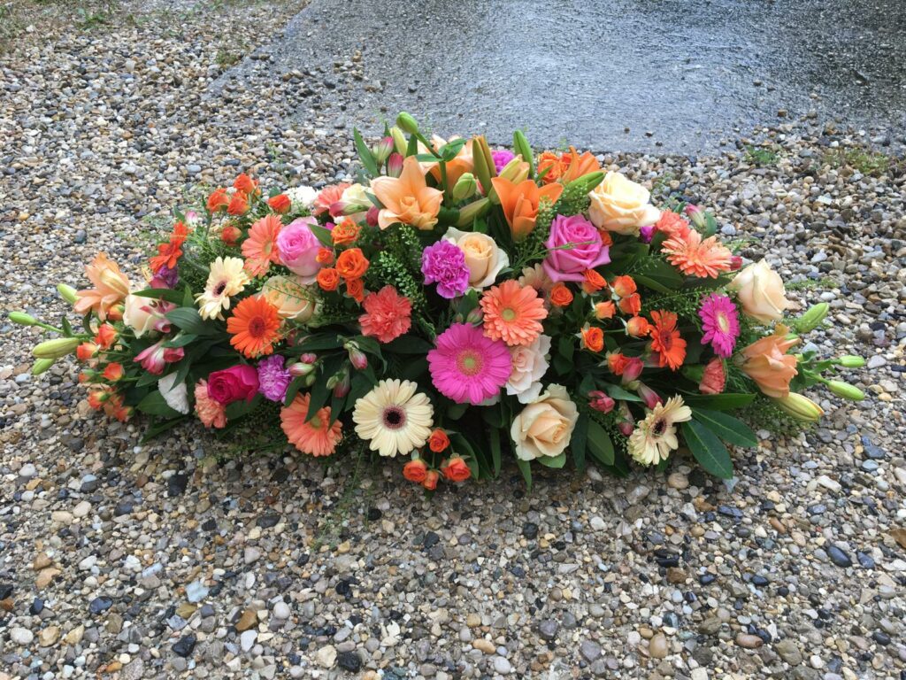 Dessus de cercueil tons rose soutenu avec des roses, des germinis, du lisianthus et de l’alstromeria